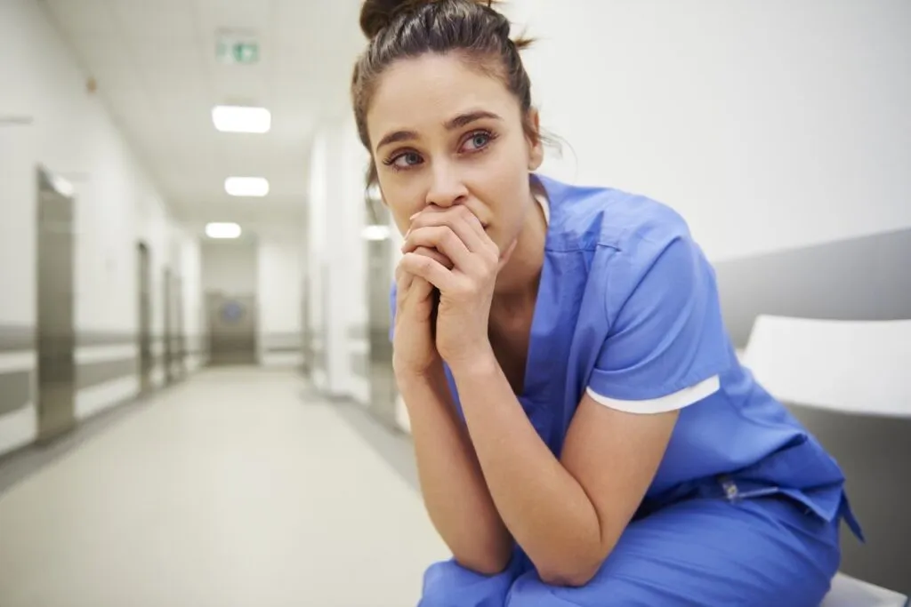 worried nurse in blue scrubs